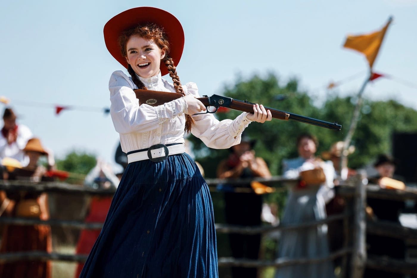 An actress as Annie Oakley holding a rifle on set
